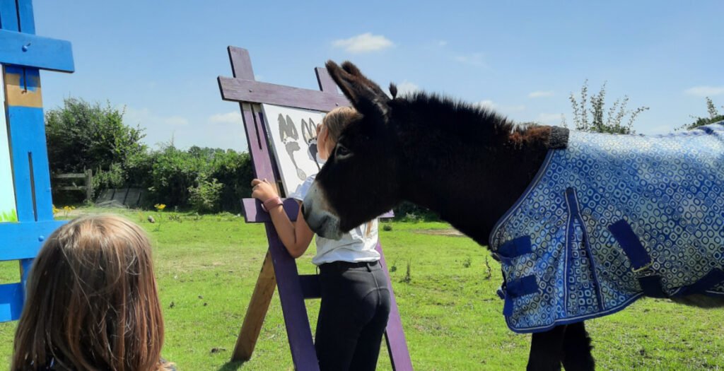 kinderen en ezel schilderen buiten in het veld