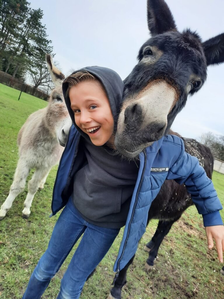 Jongetje met een ezel die meekijkt over zijn schouder